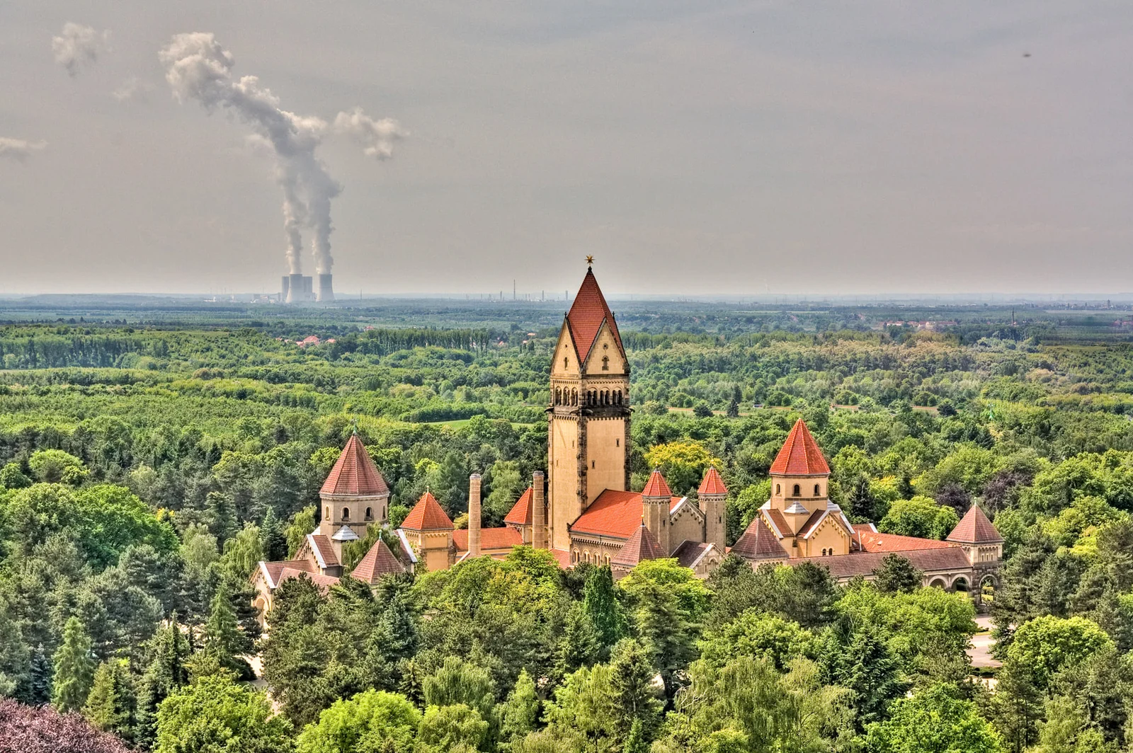 Blick von oben auf die Kapellenanlage mit hohem Mittelturm über dichtem Grün auf Südfriedhof Leipzig